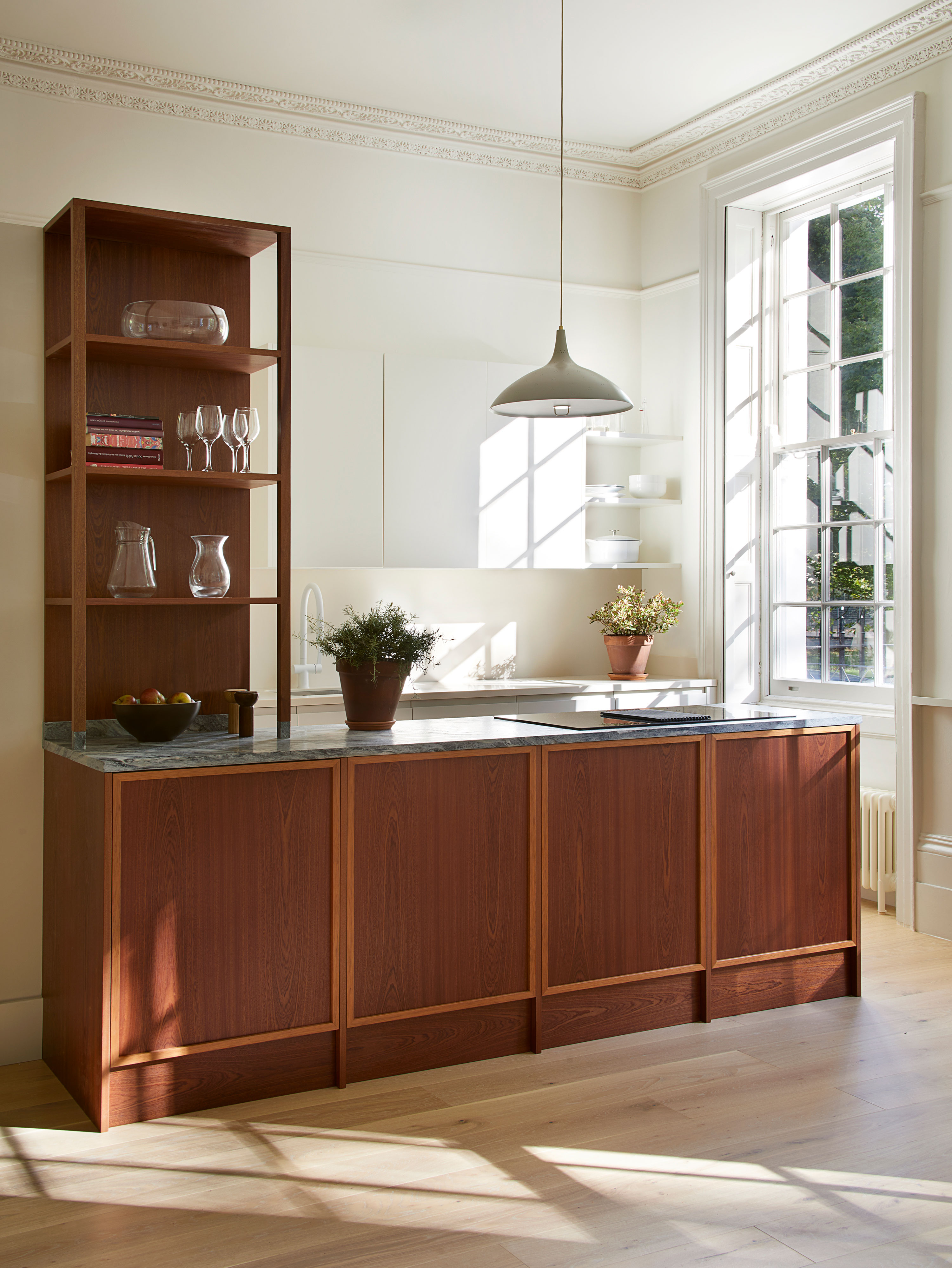 Dark wooden kitchen with sunlight over worktop and large window