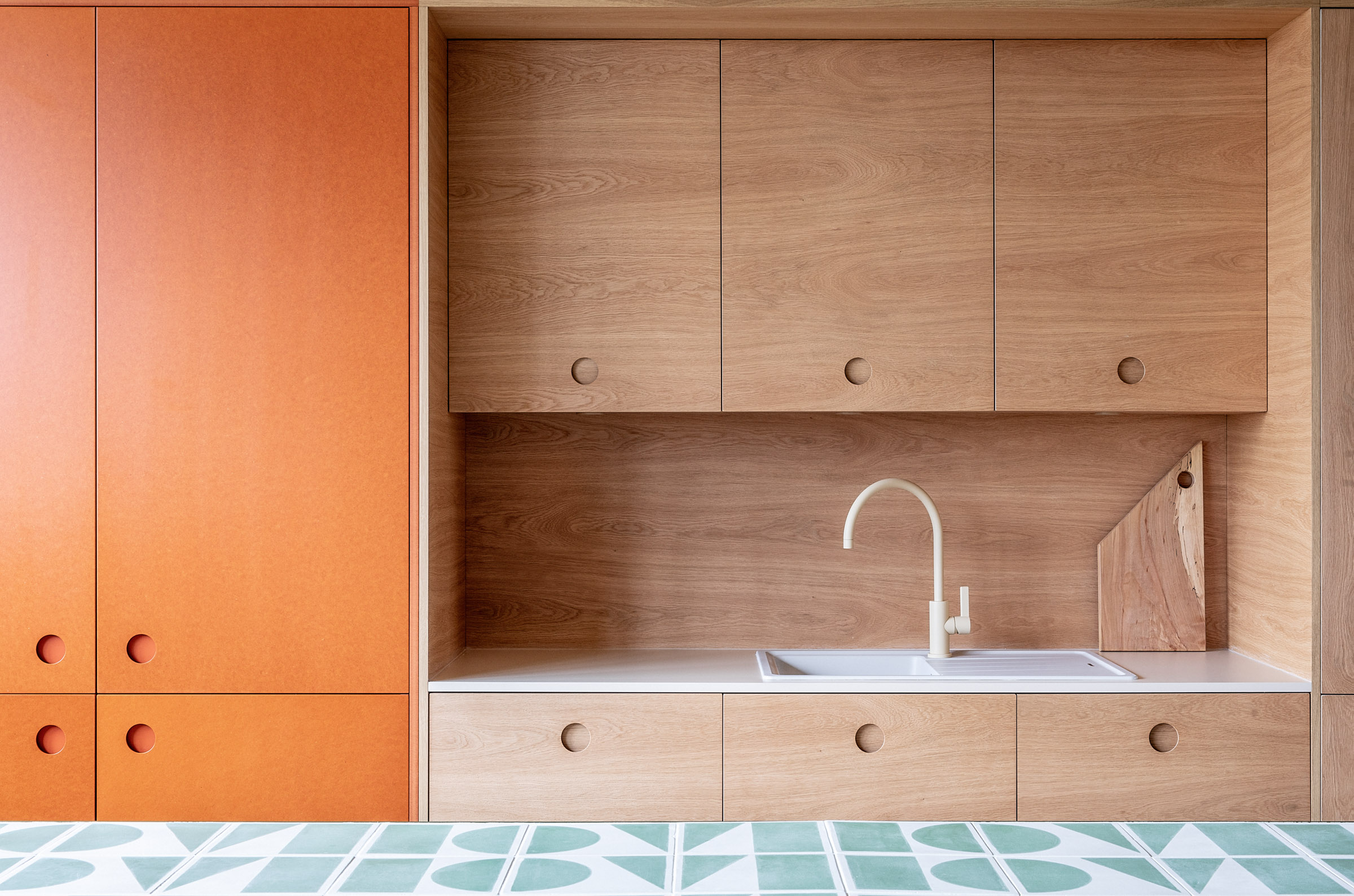 Wood and orange kitchen fronts with tiles table in foreground