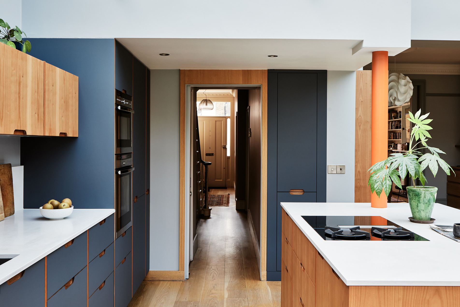 blue kitchen cabinets, quartz worktop view into hallway