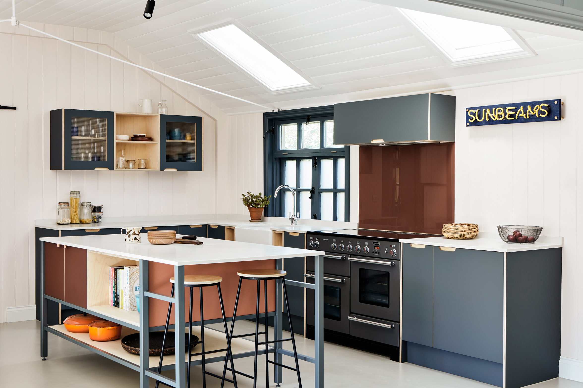 Terracotta and stone blue kitchen with large window and island and stools