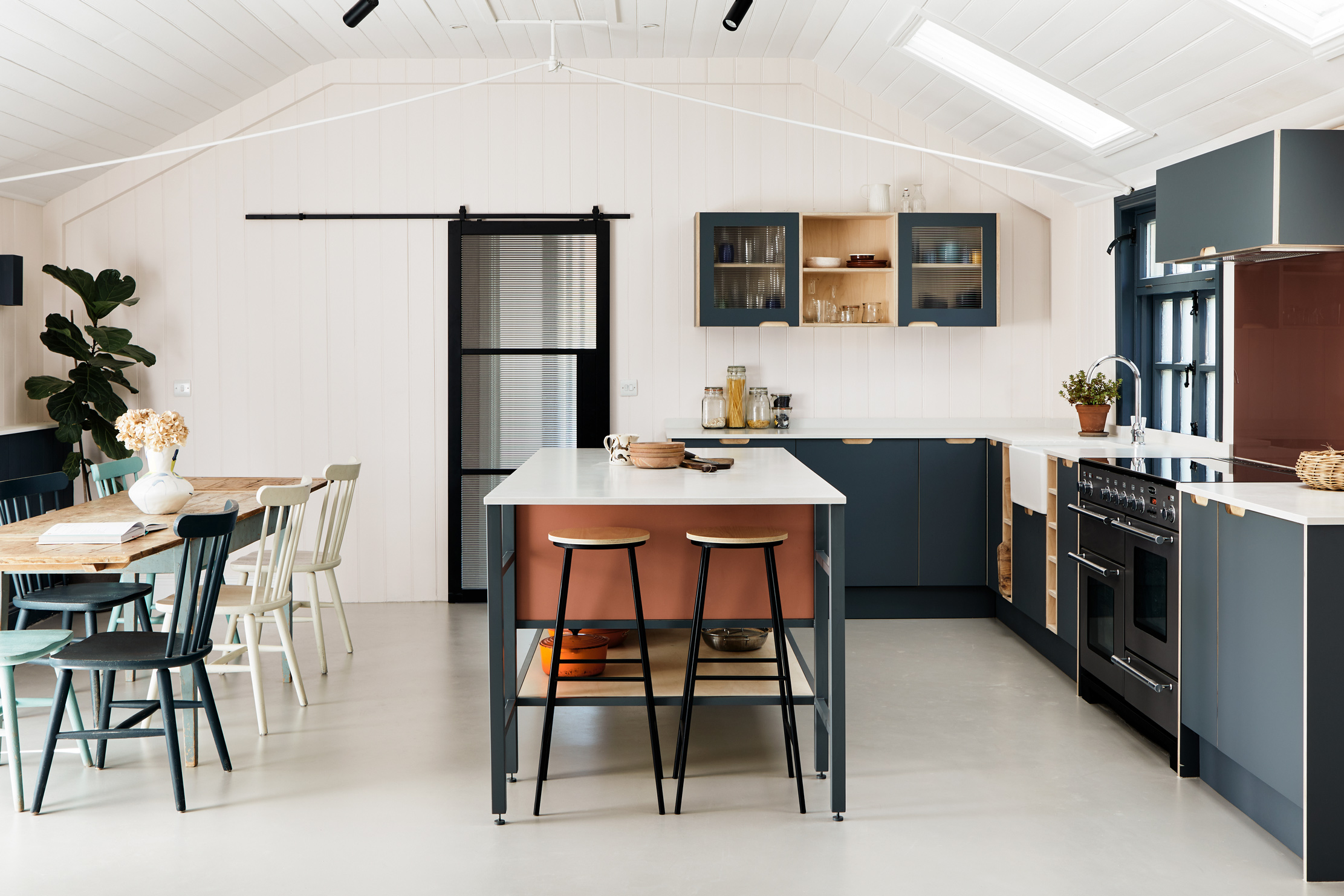 Terracotta and stone blue kitchen with large window and island and stools