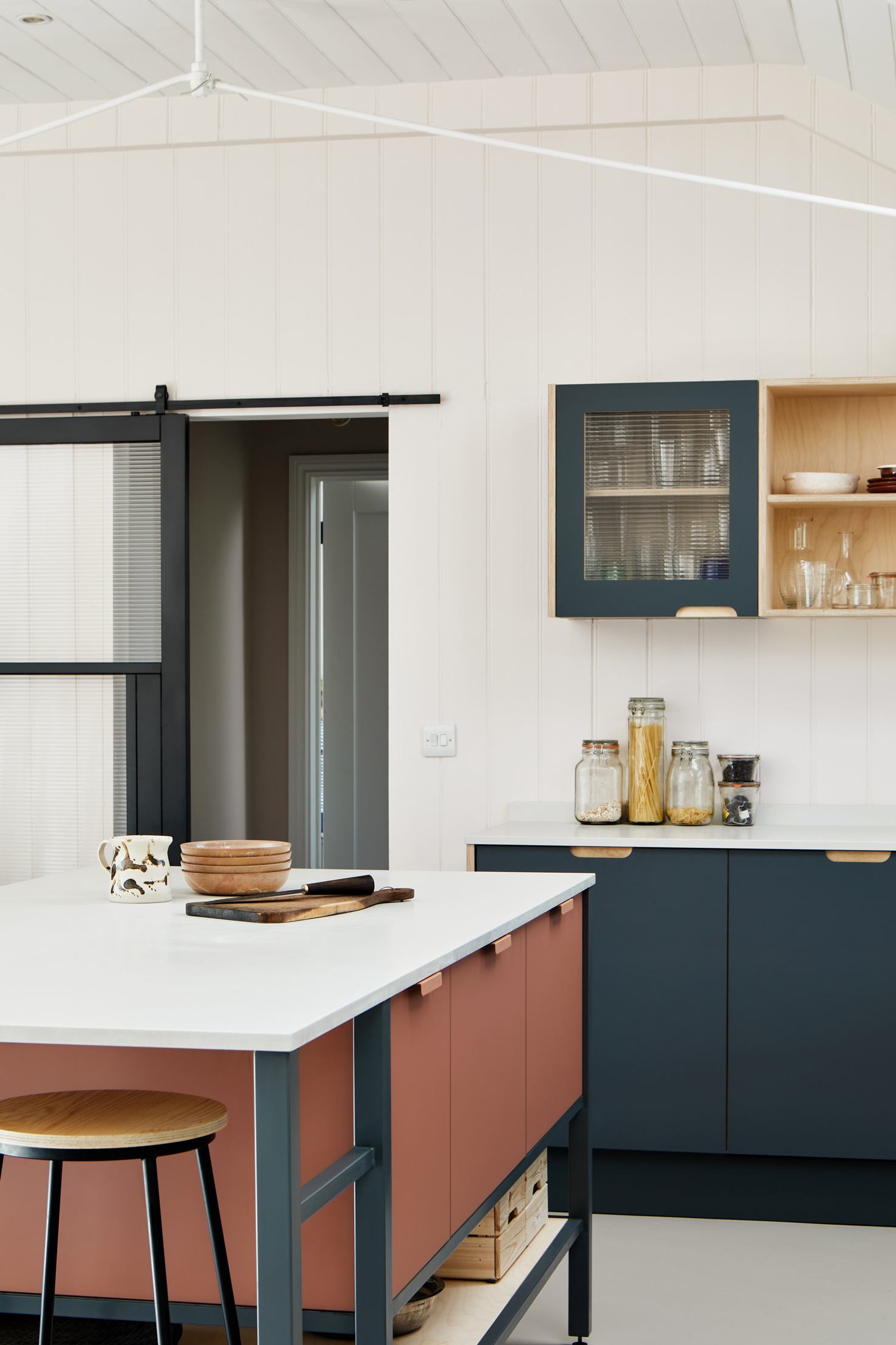 Terracotta and stone blue kitchen with large window and island and stools