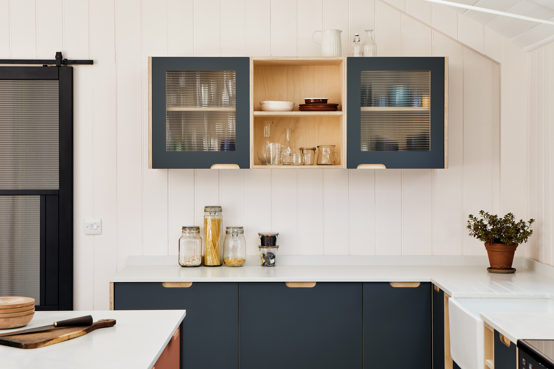 Terracotta and stone blue kitchen with large window and island and stools