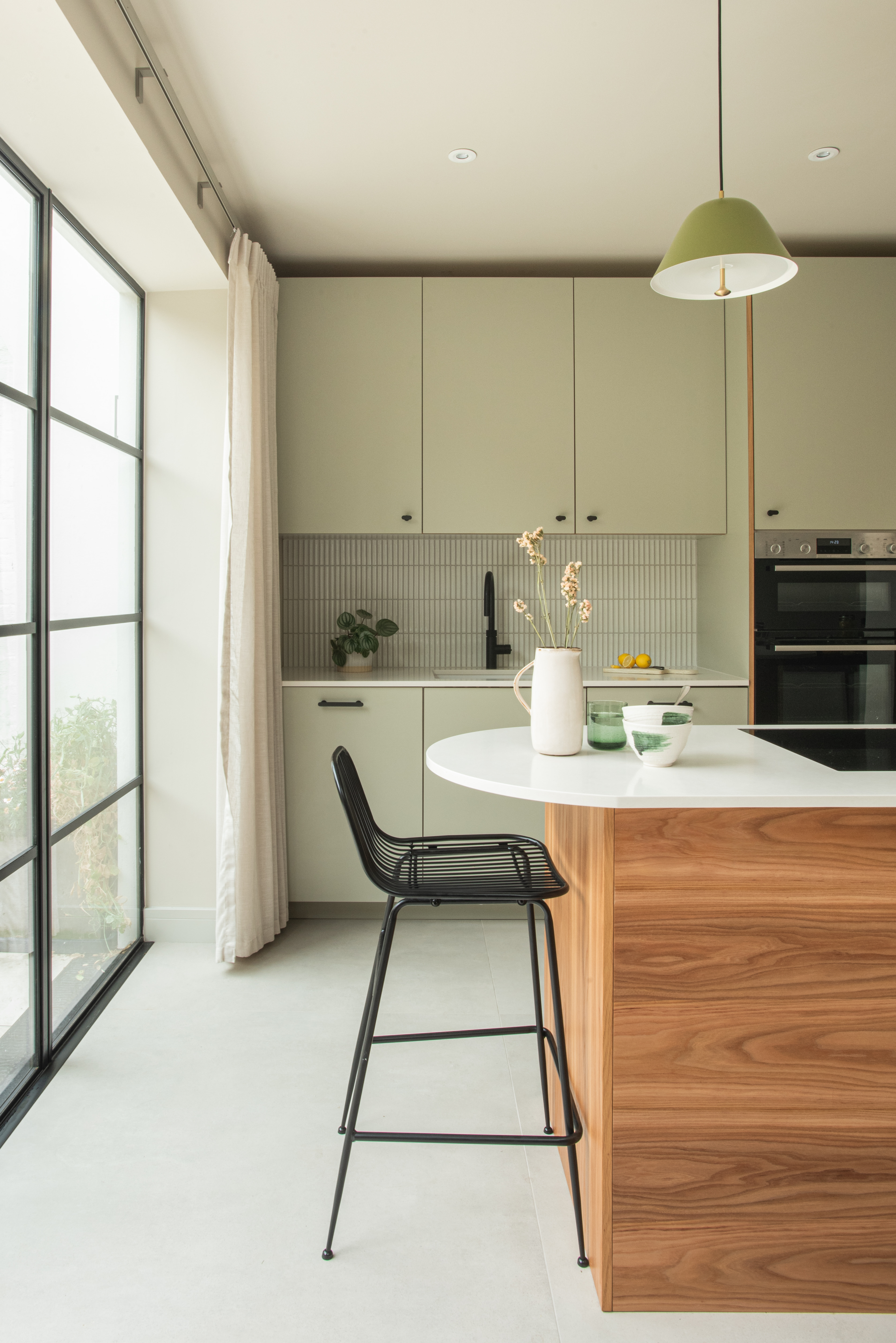wood and green kitchen with island and external doors to garden