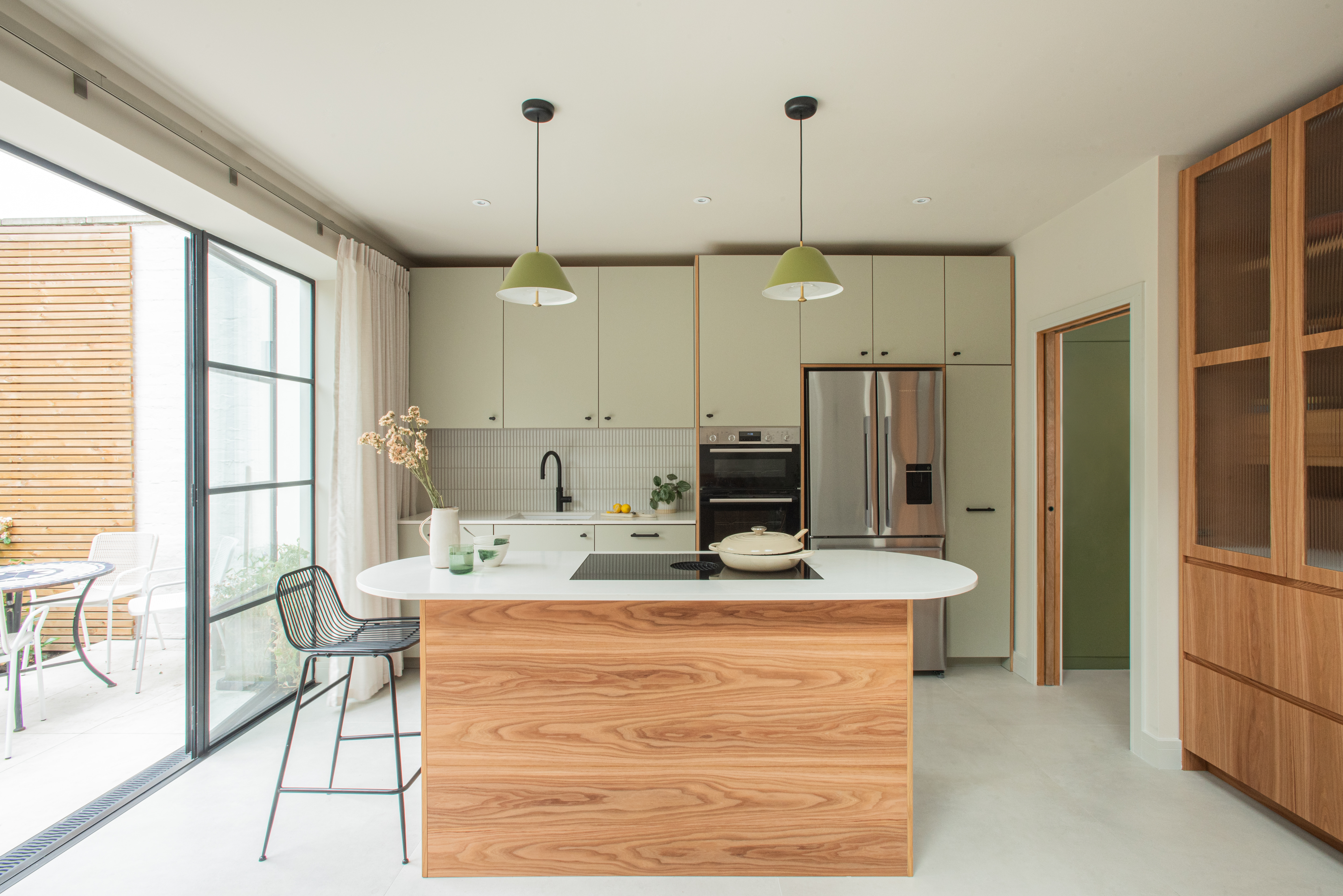 wood and green kitchen with island and external doors to garden