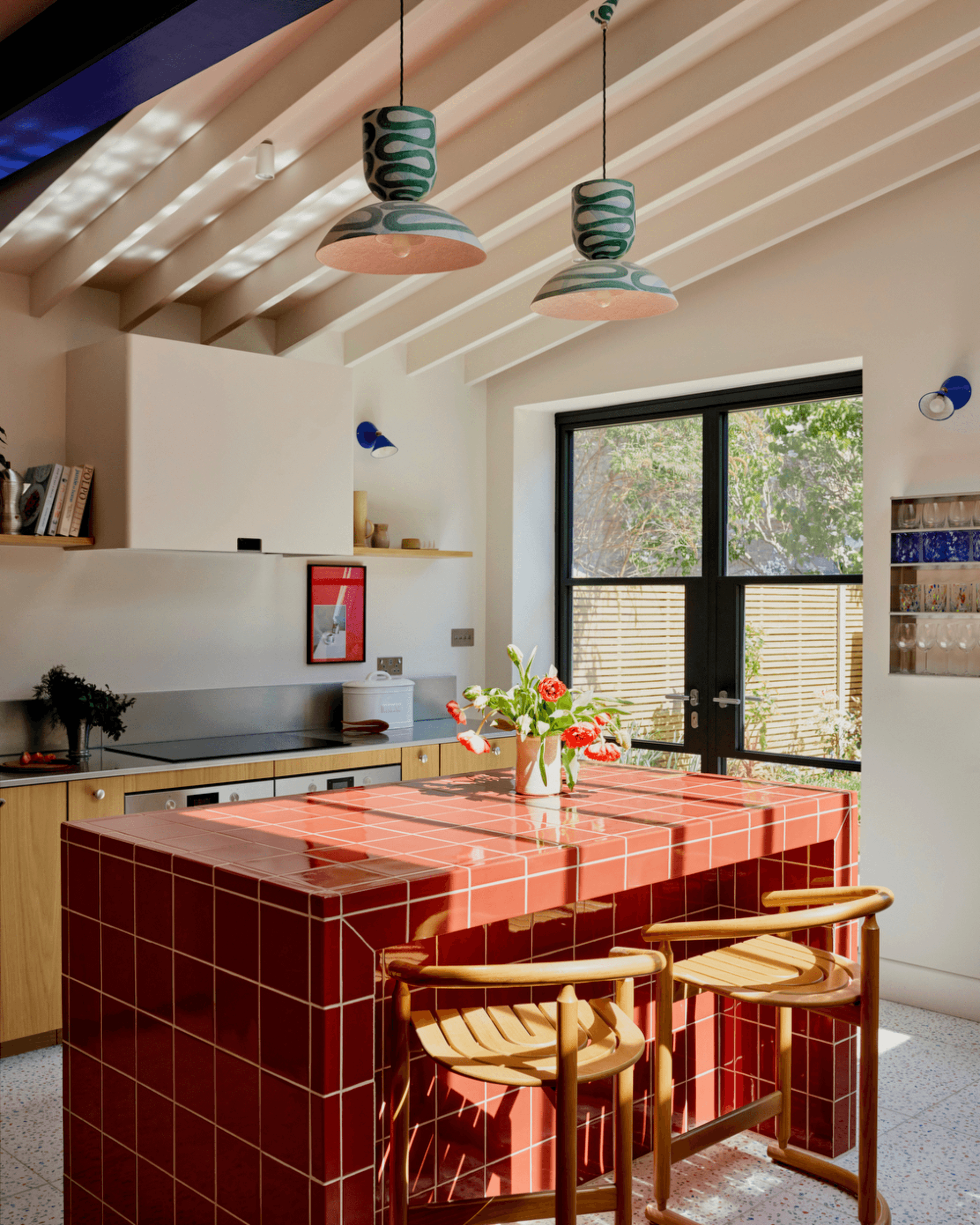Kitchen featuring red tiled island, oak veneer fronts and stainless steel worktop.